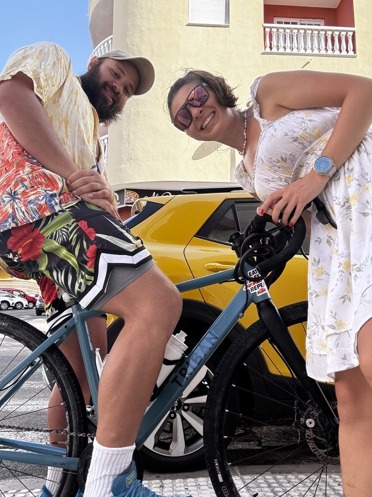 Anca handing her touring bike to a smiling Argentinian traveller in Tenerife