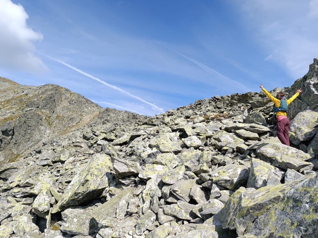 Anca with arms raised on a vast boulder field in the Retezat, Romania